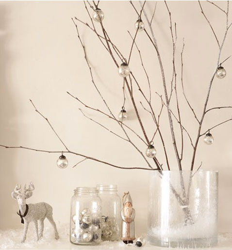 Une décoration de Noël facile à faire avec quelques petites branches d'arbre et des boules transparentes pour décorer la cheminée
