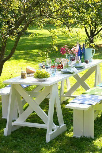 Un salon de jardin en palette pour des déjeuners bucoliques. L’ensemble plateau de table, tréteaux et banc de jardin est fabriqué avec des palettes de récup puis peint avec une peinture blanche