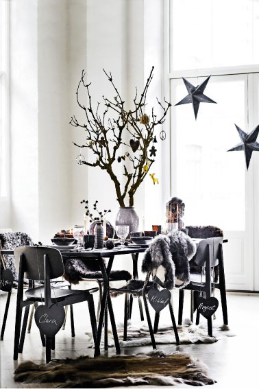 Une table de Noël en total look noir des sets de table à la vaisselle c'est chic et tendance avec des paillettes et des mini boules couleur or.