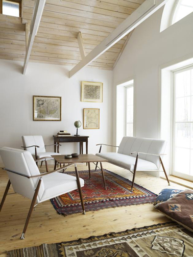 Une harmonie couleur pour un salon d'inspiration scandinave entre blanc pur et chêne clair. Tapis et coussins de sol apportent une touche de couleurs rouge et marron