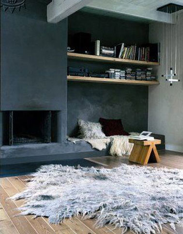 Dans ce salon moderne, un gris ardoise recouvre l'ensemble du mur intégrant également la cheminée pour un contraste forte avec les autres murs gris perle. Le parquet chêne clair ainsi que les étagères bois apportent la note chaude