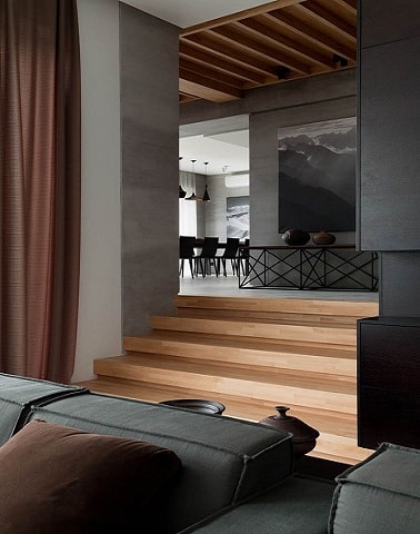 Couloir et salon couleur gris anthracite déco moderne Dans un salon moderne et jusqu'au couloir, la couleur gris étale ses nuances. Le gris anthracite design peint sur les murs s'accorde avec les marches de l'escalier en bois.