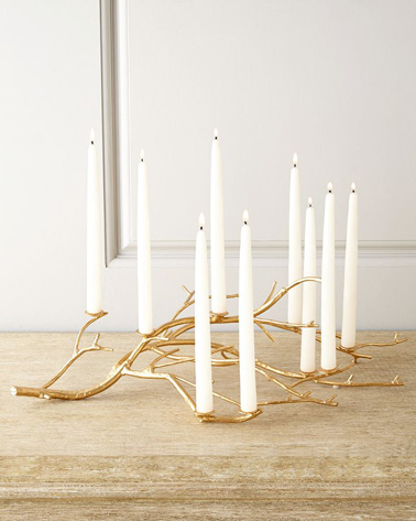 Sublimez votre déco de table de Noël en fabriquant un porte-bougies à l’aide d’une branche. Bombez-la de doré et fixez des bougies blanches avec des clous pour une table qui scintille de milles feux