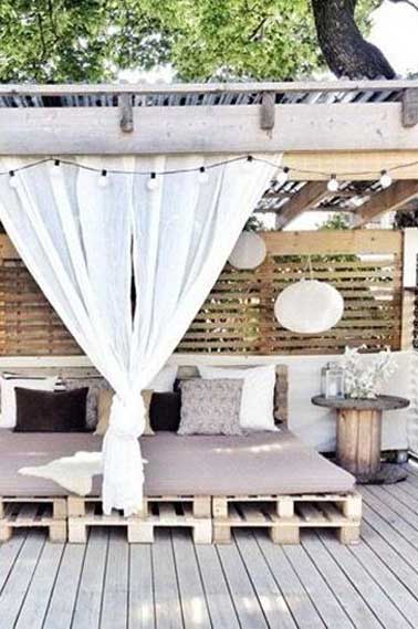 Ambiance cocooning et déco extérieur nature, avec ce salon de jardin en palette installé sous le patio d'une terrasse en bois