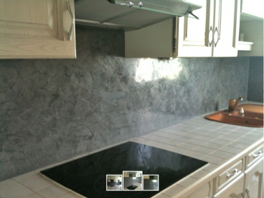 Pour repeindre entièrement cette cuisine, meubles bois et plan de travail en carrelage une même peinture ivoire. La crédence à l’allure moderne est repeinte avec de la chaux ferrée grise ultra brillante.