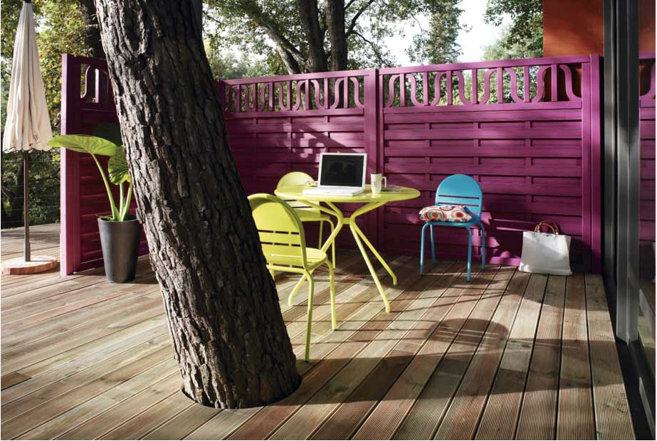 Palissade bois déco pour l'aménagement d'une terrasse intime Pour aménager une terrasse dans le jardin, une palissage bois peinte couleur prune et mobilier de jardin couleur vert et bleu