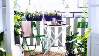 Déco balcon en ville avec table et chaises de jardin Ikea Un brise vue en tissu rayé blanc et gris, des chaises et jardinières de couleurs vives pour un balcon sympa, les dalles en bois clipsables ajoutent du confort et mettent en valeur le mobilier de jardin Ikea vert prairie et blanc