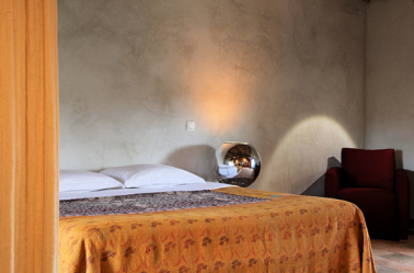 decoration d'une chambre à coucher grise égayée par un plaid et des rideaux orange et un fauteuil gris foncé