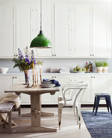 Dans une cuisine rustique les meubles repeints en blanc, la table de ferme et son banc en bois ajoutent une note chaleureuse de campagne chic