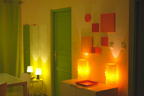une salle a manger couleur peinture jaune pour les murs porte et encadrement couleur vert luminaire et tableaux decoratifs orange
