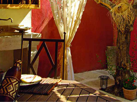 cuisine d'ete exterieur style provencal, peinture mur couleur ocre rouge, table en teck, chaise de jardin en fer,evier pierre