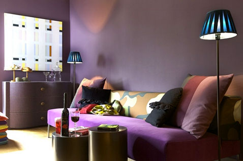 Pour une déco chic dans le salon, la couleur violet est mise à l'honneur avec une peinture couleur prune associée à une teinte figue, un canapé violet et coussins noirs