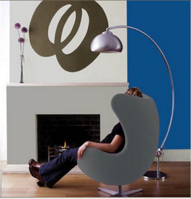 salon decoration design avec une composition de nuances de gris pour les peinture murale, cheminée contemporaine fauteuil coque revetement tissu gris lampadaire acier brossé