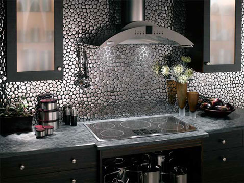 Avec des meubles de cuisine teintés wengé, la crédence carrelage inox en forme de petits galets, assorti à la hotte de cuisine design en inox et plaque à induction.