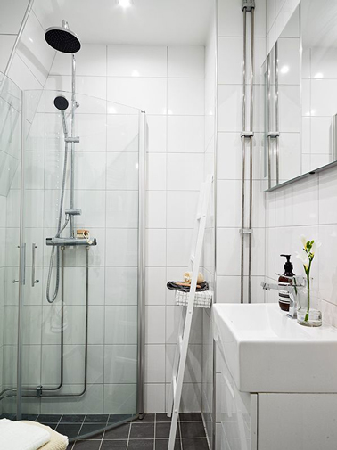 Déco d'une petite salle de bain avec  du carrelage blanc sur haute la hauteur des murs et paroi de douche posée en angle pour gagner de la place