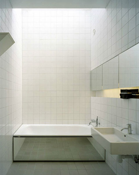 salle de bain design avec carrelage blanc sol et mur pour habiller le tablier de la baignoire un grand miroir qui rappele les portes miroirs des placards
