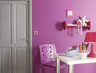 La porte de la chambre peinte en gris galet associé à une peinture murale de couleur rose flashy. A utiliser en touche, le rouge de l'étagère et de la lampe de bureau