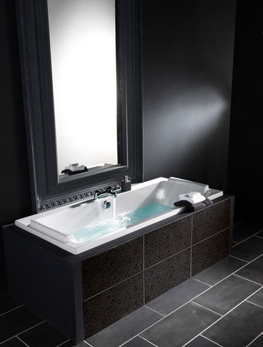 Une salle de bains total look noir avec peinture murale noir intense, carrelage sol en pierre noire. L'encadrement du grand miroir à été peint en noir complète le style baroque. 