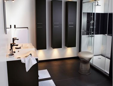 Pour une salle de bains design en noir et blanc, un mobilier noir aux lignes très épurées, un sol noir ardoise qui offre un contraste fort avec le blanc pur des éléments sanitaires de la peinture mural et du linge de toilette.