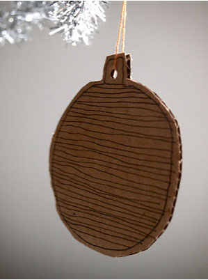 Boule de Noël réalisée avec du carton ondulé et décorée au stylo noir à crocher dans un sapin de Noël blanc ou argenté