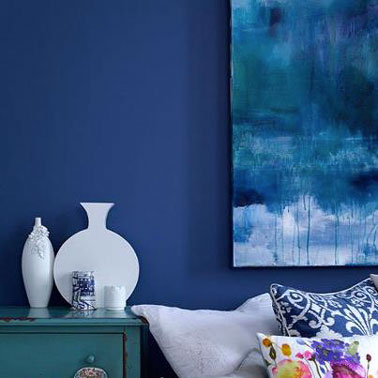Une décoration de salon qui se décline autour du bleu. Au mur peinture couleur Monaco blue, tableau bleu et blanc, commode couleur bleu turquoise, serie de vases blancs