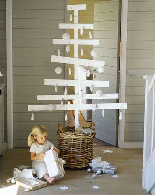 Pour une décoration de Noël de style épuré, un sapin de Noël réalisé avec des planches de bois peintes en blanc. Boules et décorations en blanc également