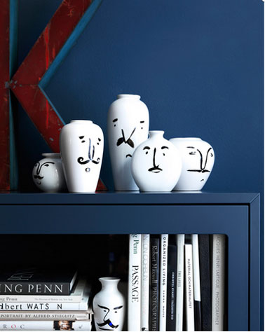 Pour agrandir le salon, la bibliothèque et les murs sont peints dans la couleur, Le bleu monaco. La série de vase blanc apporte un contraste fort.