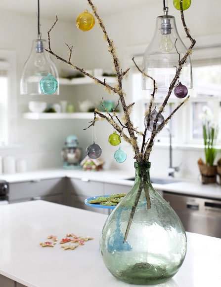 Une idée de décoration de Noël facile à réaliser avec un bouquet de branchage et des petites boules de Noël multicolores à poser sur la table de salle à manger ou de cuisine