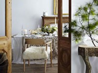 Dans un séjour zen, la déco de table de Noël se fait à l'unisson, nappe en coton et lin, bougie blanche et déco du centre de table avec une composition de feuillages légers