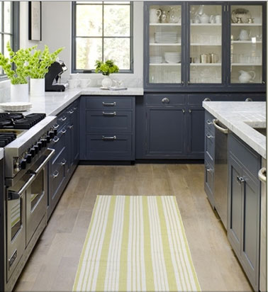 Cuisine en L avec îlot, meubles gris, murs peinture blanche, sol parquet flottant blond touches de jaune avec tapis et fleurs