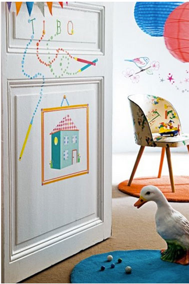 Sur la porte d'entrée de la chambre d'enfant dessins et gommettes reprennent les décorations murales de la chambre  