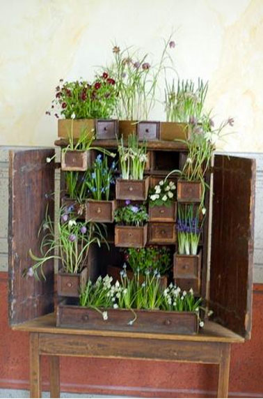 Comment utiliser un meuble ancien pour aménager un jardin sur un petit balcon : Laisser les portes du meubles ouvertes et remplir les tiroirs de terre après les avoir protégé d'une bâche plastique, puis planter bulbes à fleur, plantes aromatiques