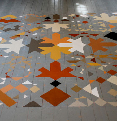 Pour repeindre le parquet de ce salon, un beau jeu de motifs réalisé avec quatre couleurs de peinture pour imiter un tapis au sol