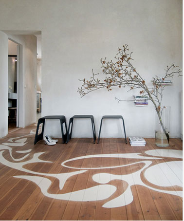 Parquet salon design décoré de grande arabesques peintes en blanc sur parquet couleur chêne moyen