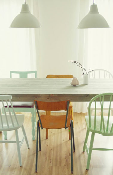 Une déco de salle à manger aménagée autour d'une belle couleur vert clair sur les murs, les chaises dépareillées et les 2 suspensions. Le parquet blond, ainsi que les 2 chaises laissées dans leur jus apportent la touche chaleureuse. 