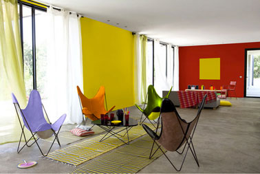 salon ambiance estivale avec peinture mur couleur jaune vif et rouge. 