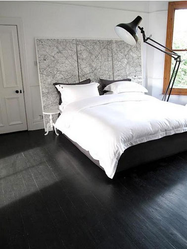 chambre avec parquet de frêne noir, linge et lit et murs blanc. Tête de lit réalisée avec une grande carte routière.