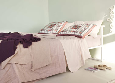 Déco chambre dans une harmonie de tons pastel. Aux murs, une peinture de couleur vert jade associé à du linge de lit aux couleursdiluées. Jeté de lit en lin rose tendre, taies d'oreiller à petits carreaux blanc, rose tendre et rose soutenu