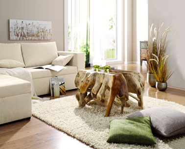 Décoration d'un salon aux couleurs naturelles et zen. Canapé en cuir et tapis de laine couleur écru. la table basse est réalisée en bois flotté dans le même ton que le parquet de chêne.