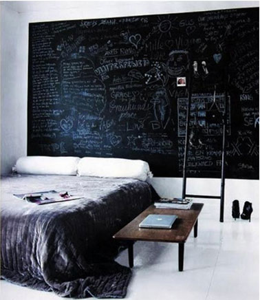 Chambre d'adulte en noir et blanc. Tête de lit peinte sur mur avec peinture à tableau noir, décorée de graffitis à la craie blanche 