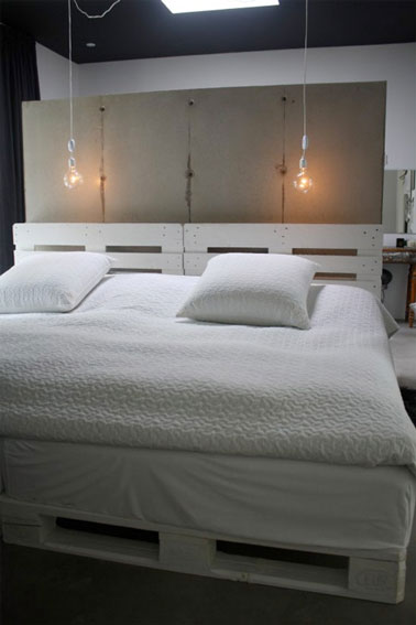 Le sommier en palettes est dissimulé par un couvre sommier, mettant en valeur les deux palettes peintes en blanc constituant la tête de lit