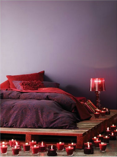 Ambiance romantique dans la chambre avec des palettes bois pour accueillir le matelas et la lampe de chevet