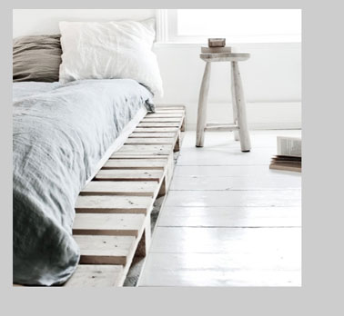 Dans une chambre zen grise et blanche, les palettes du lit sont lasurées en gris clair et posées directement sur le parquet