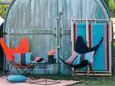 fauteuils en toile pliants couleur bleu, noir. coussins à rayures de couleurs vives bleu, rouge. Table basse métal noir laqué