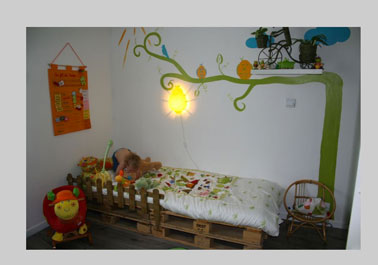 Lit chambre petite fille réalisé avec des palettes bois. La petite barrière de protection est réalisée avec des tasseaux plats teintés en marron