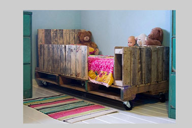 Original, sécurisant et pas cher, un lit en palette dans une chambre de jeune enfant. Une rangée de traverses récupérées sur des palettes assure la sécurité de l'enfant et le pied offre l’occasion d’un rangement pour les jouets et peluche.