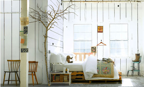 Déco chambre style scandinave avec lit réalisé avec des palettes de bois laissées brutes.Linge de lit blanc pur, chaises vintage complètent la décoration