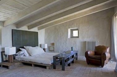 lit en palette bois assorti à la table de chevet et à la console de lit Dans cette chambre, pour compléter le lit en palette bois, la console de pied de lit et la table de chevet sont aussi fabriquées avec des palettes. Pour le chevet, la palette est recouverte d'une planche de bois pour une meilleure stabilité de la lampe sur pied.