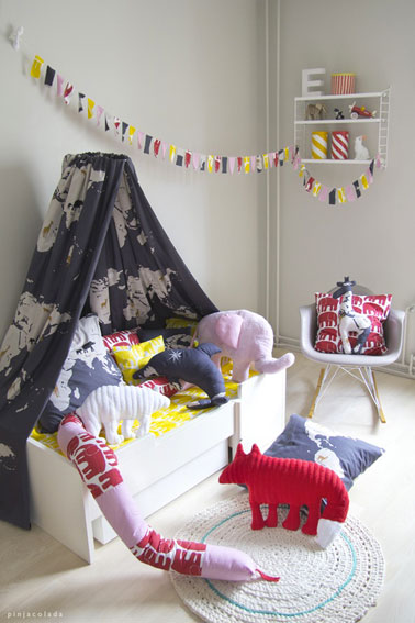 Pour contraster avec les couleurs neutres de cette chambre d'enfant, une guirlande réalisée avec des carrés de tissus de couleur.