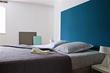 Deco chambre couleur gris, blanc et bleu. La tête de lit est peinte en un grand carré bleu "Enamuel Blue" couleur tendance inspirée by Pantone chez Tollens. Linge de lit gris clair et anthracite